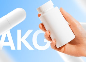 Hand holding white AKG pill bottle in blue background