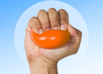 Hand squeezing a stress ball set against a blue background