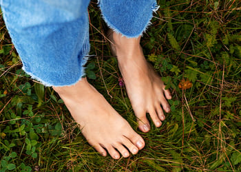 Person with bare feet standing on the grass in the forest