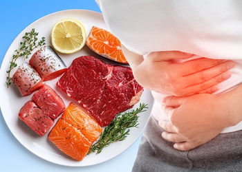 A plate with different types of meat and fish next to a person experiencing stomach ache
