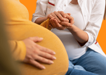 A healthcare professional holding a pregnant woman's hand