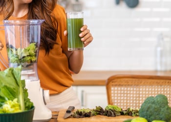 Woman blending green vegetables to make juice
