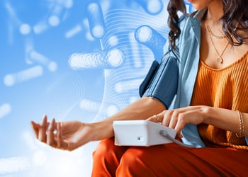 A person measuring her blood pressure and probiotic pills in the background