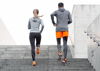 Two people running up the stairs outside in gym clothes