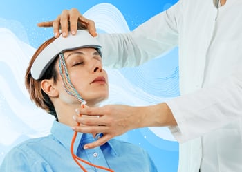 Person sitting with neurofeedback device wired to the head while doctor stands near