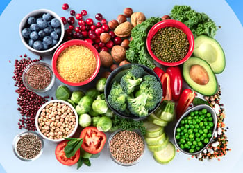 Different types of fiber, including broccoli, seeds and nuts, set against a blue background