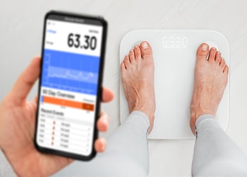 Person standing on a smart scale and checking the result on their phone
