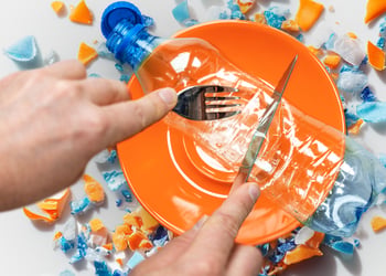 Person cutting a plastic bottle with a fork and a knife