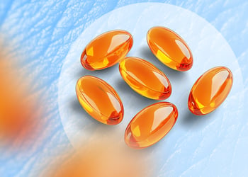 Orange omega-3 supplements on blue skin textured background