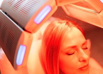 Person using a red light therapy device for their hair and scalp