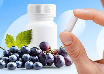 Blueberries near a white blank bottle, hand holding resveratrol supplement in blue background