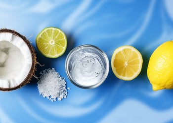 Coconut, lime, lemons, and salt crystals on a blue and white swirl background
