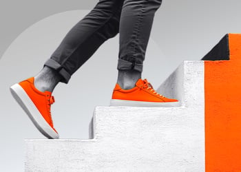 Person climbing a staircase, wearing bright orange shoes