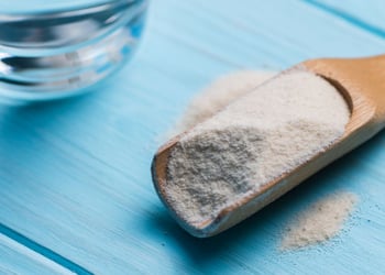 Psyllium husk and glass of water on blue wooden background