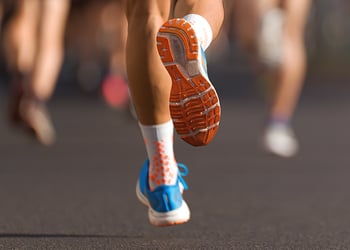 Feet wearing orange and bleu sneakers running in a marathon