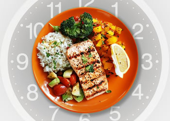 Orange plate full of omad diet food with clock in the background