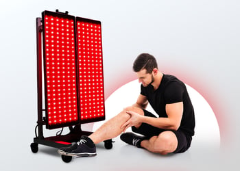 Person on the ground feeling their knee for pain next to a big red light device