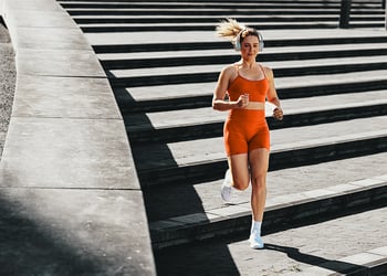 Person in orange sportswear running down the stairs