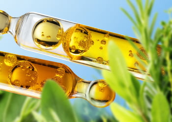 Two ampules of yellow liquid and green plants on a blue background