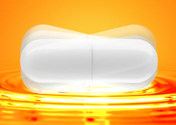 A white large capsule in motion on an orange background
