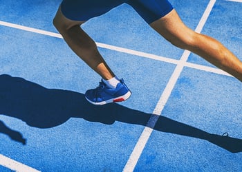 Person running on blue track field