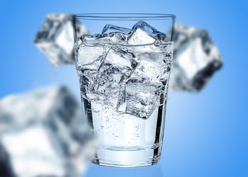 Glass of ice water in blue background