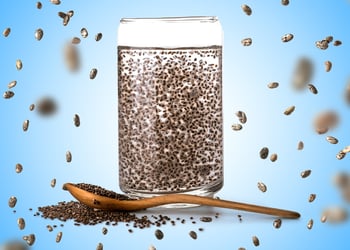 Chia seeds in a water cup with a spoon besides