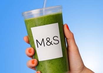 A hold holding a glass of green juice
