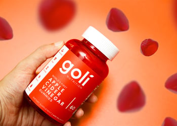 A hand holding a bottle of Goli apple cider vinegar gummies