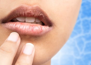 A close up of a woman's mouth and fingers next to it