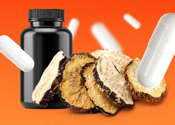 Black maca root and a black bottle with supplement pills on an orange background