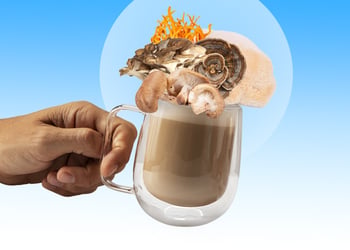 A hand holding a cup of coffee with different types of mushrooms on top of it