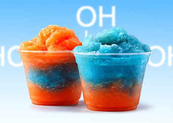 Two orange and blue slush ice drinks on a blue background