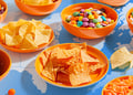 Collage of candy, tortilla chips, and Oreos in bowls on top of a world map