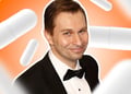 David Sinclair in a suit with orange background consisting of pills