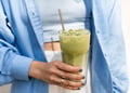 A hand holding an iced matcha latte