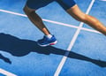 Person running on blue track field