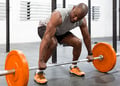 Dark skin person preparing to deadlift orange bar